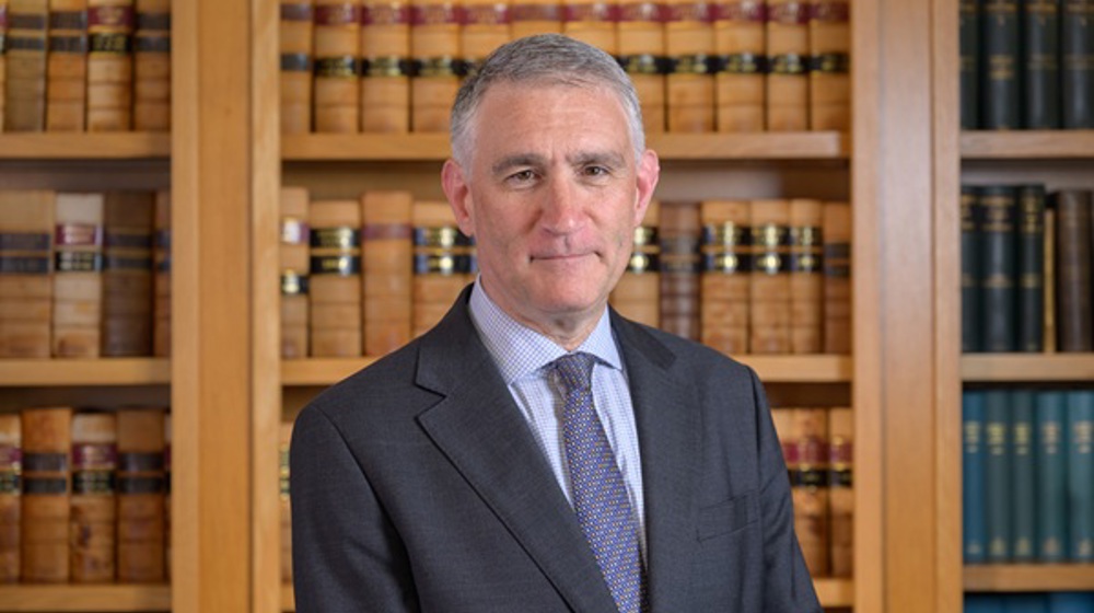 Solicitor General standing in front of bookcase